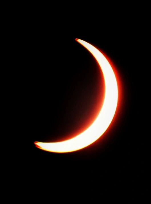 A fiery crescent of a solar eclipse against the dark sky